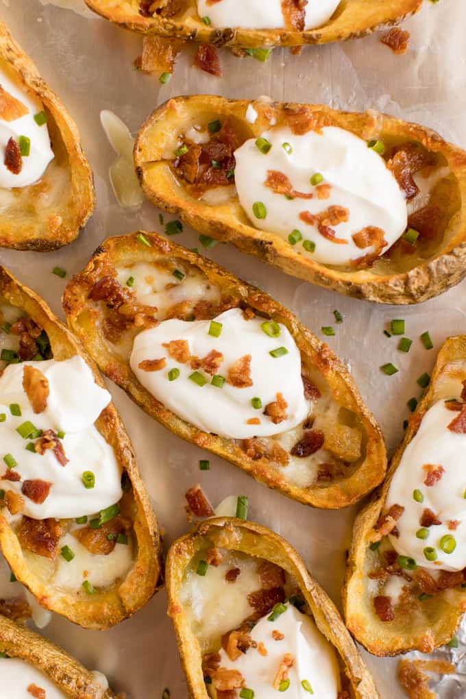 Cheesy Potato Skins - Topped with sour cream, tasty bacon and fresh green onions, this appetizer recipe is a crowd-pleasing classic.