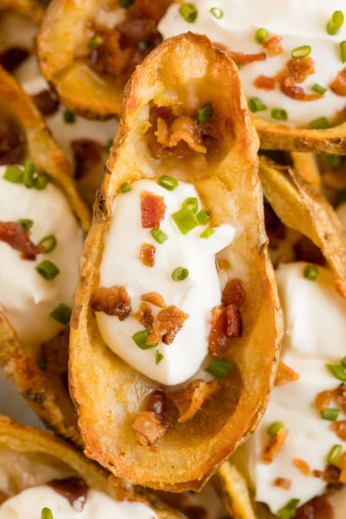 Cheesy Potato Skins - Topped with sour cream, tasty bacon and fresh green onions, this appetizer recipe is a crowd-pleasing classic.