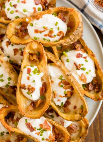 Cheesy Potato Skins - Topped with sour cream, tasty bacon and fresh green onions, this appetizer recipe is a crowd-pleasing classic.