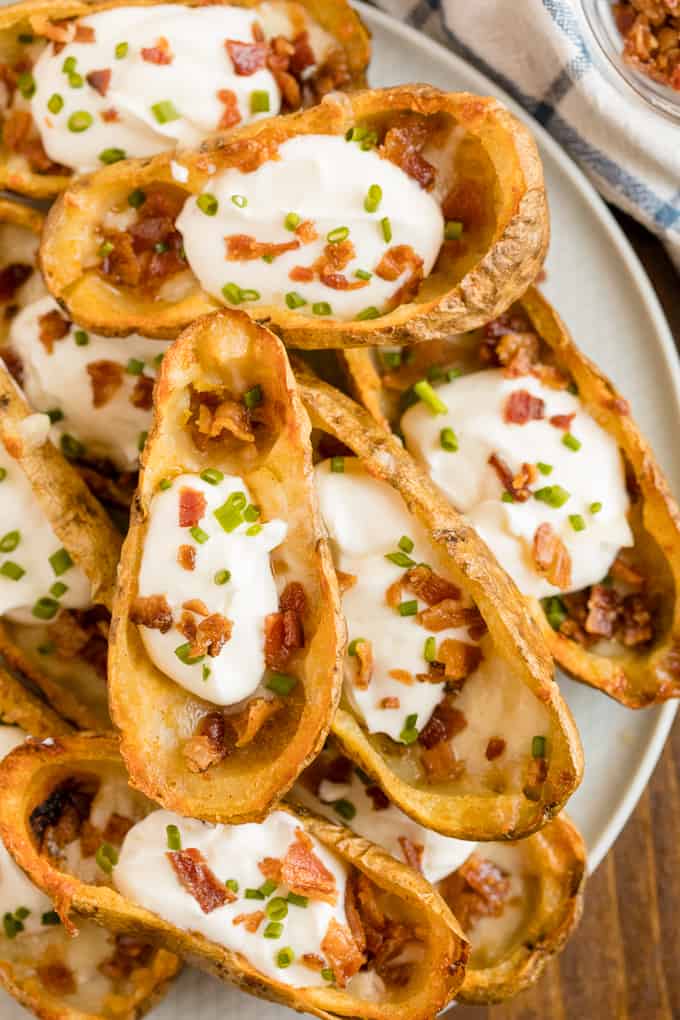 Cheesy Potato Skins - Topped with sour cream, tasty bacon and fresh green onions, this appetizer recipe is a crowd-pleasing classic.