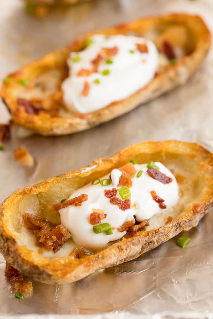 Cheesy Potato Skins - Topped with sour cream, tasty bacon and fresh green onions, this appetizer recipe is a crowd-pleasing classic.