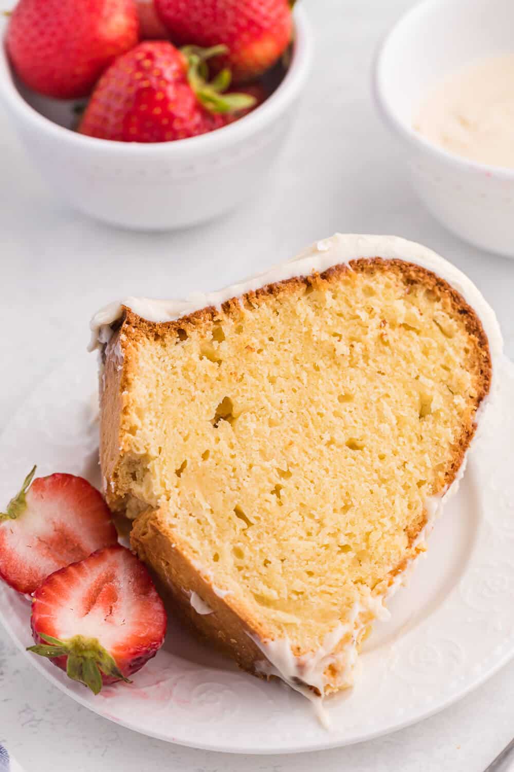 A slice of vanilla cream cheese cake on a plate with strawberries