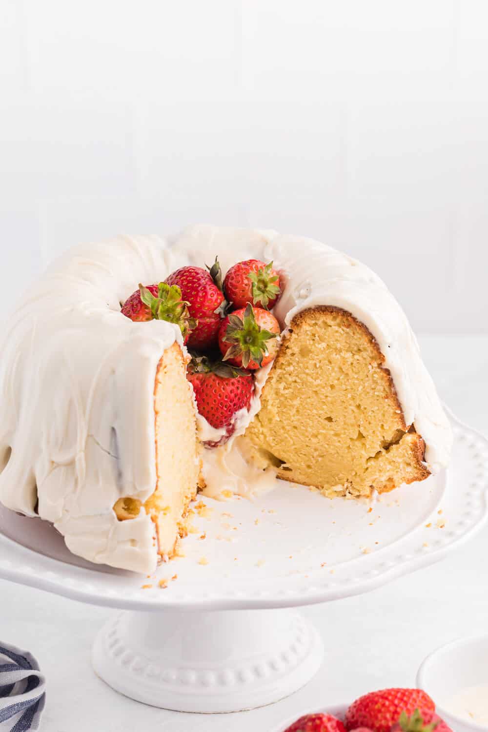 Vanilla Cream Cheese Cake on a cake stand with pieces cut out