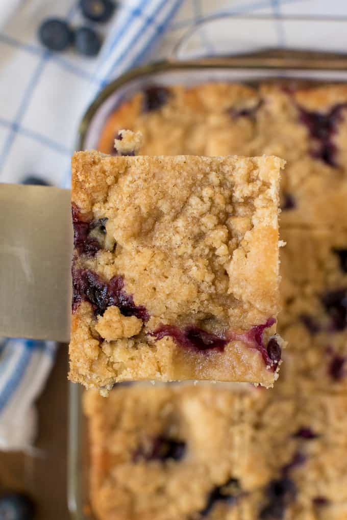 A spatula lifting up a slice of blueberry buckle.