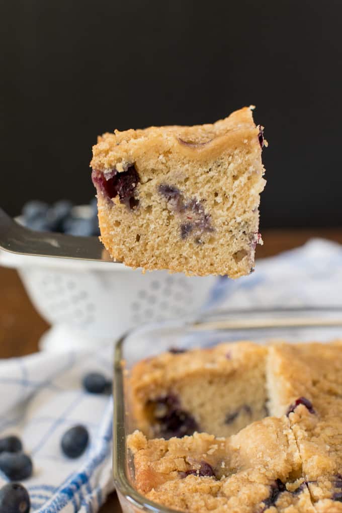 A spatula lifting out a piece of blueberry buckle cake.