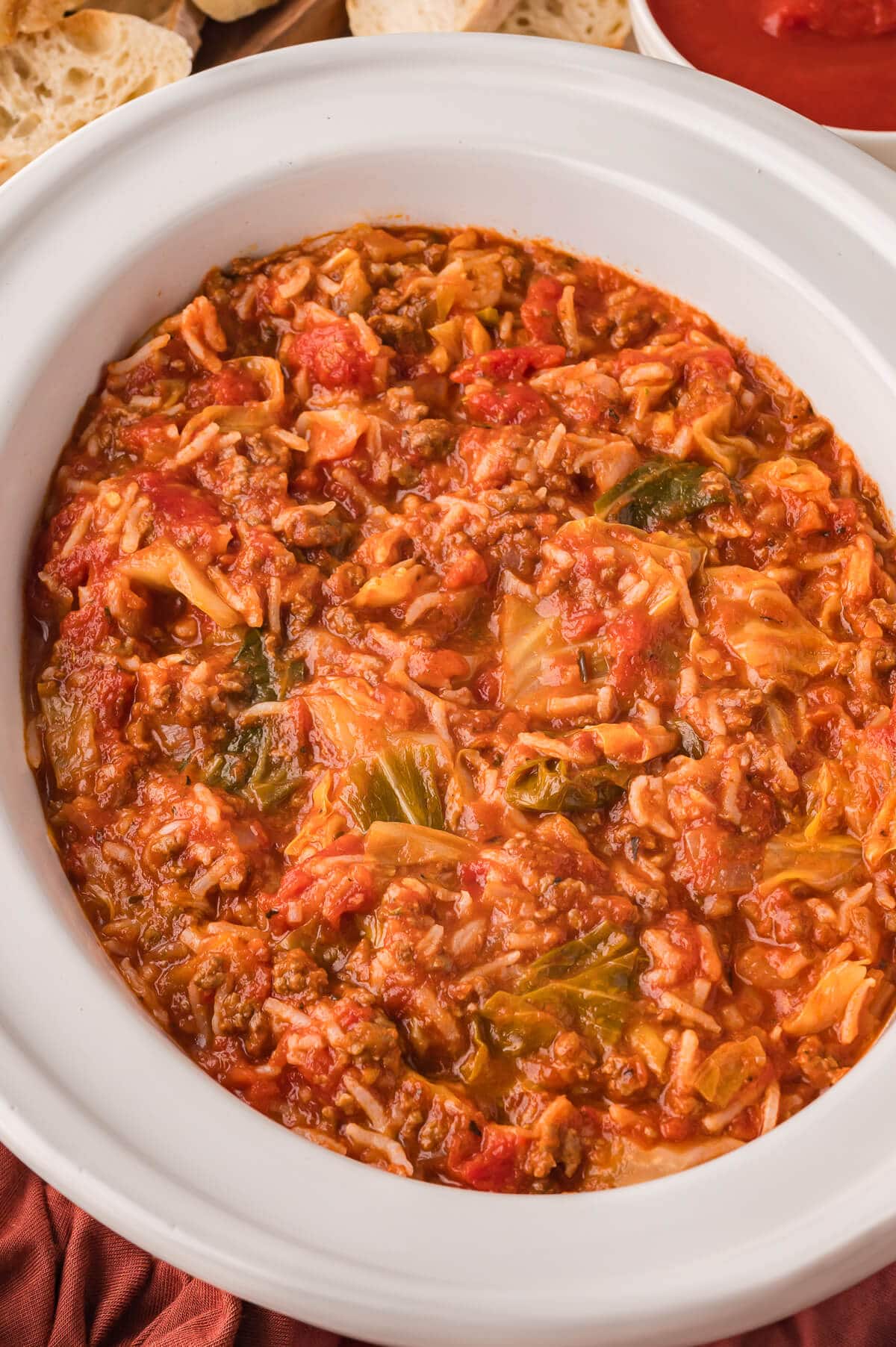 A white slow cooker with cabbage roll soup.