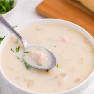 Salmon chowder in a white bowl with a spoon.