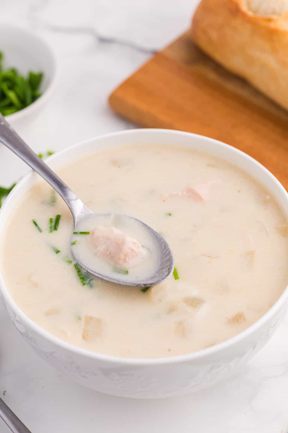 Salmon chowder in a white bowl with a spoon.