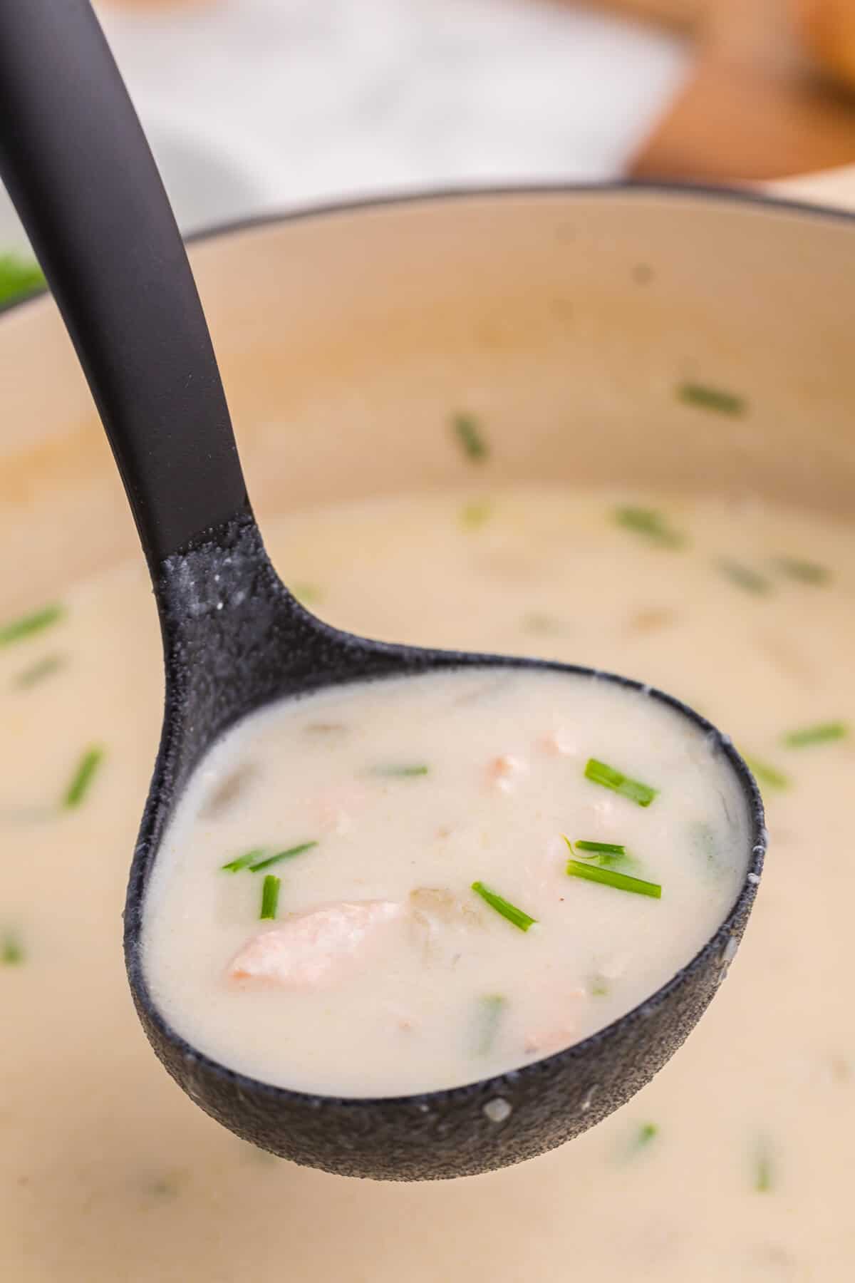 Salmon chowder in a black ladle.