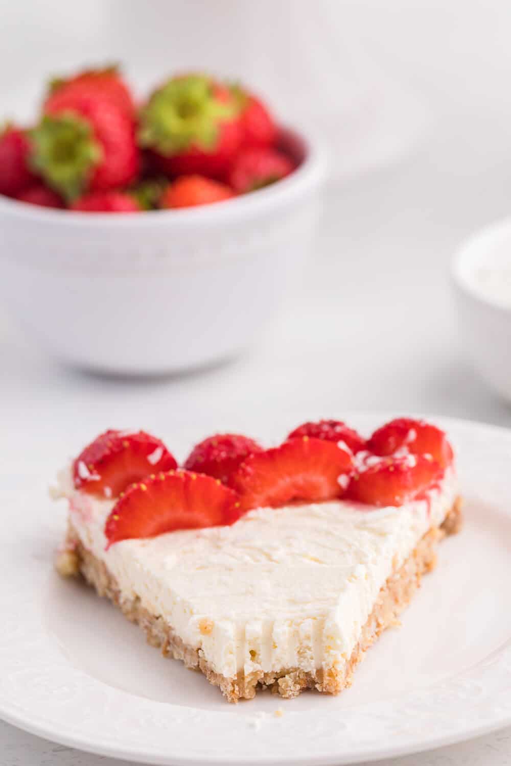 A slice of no-bake strawberry cheesecake with a bite out of the end