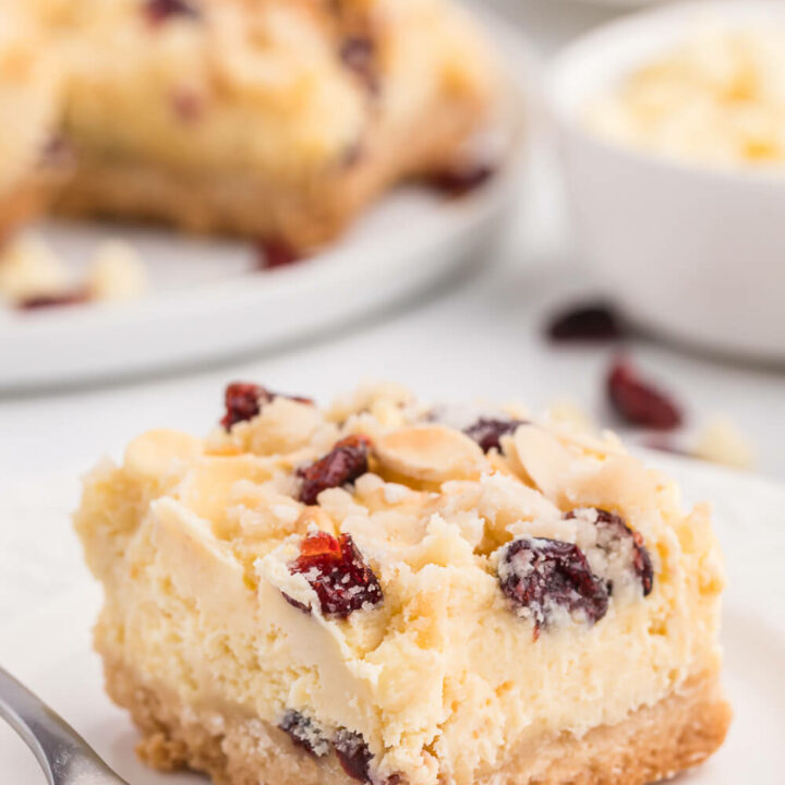 A white chocolate cranberry cheesecake bar on a white plate