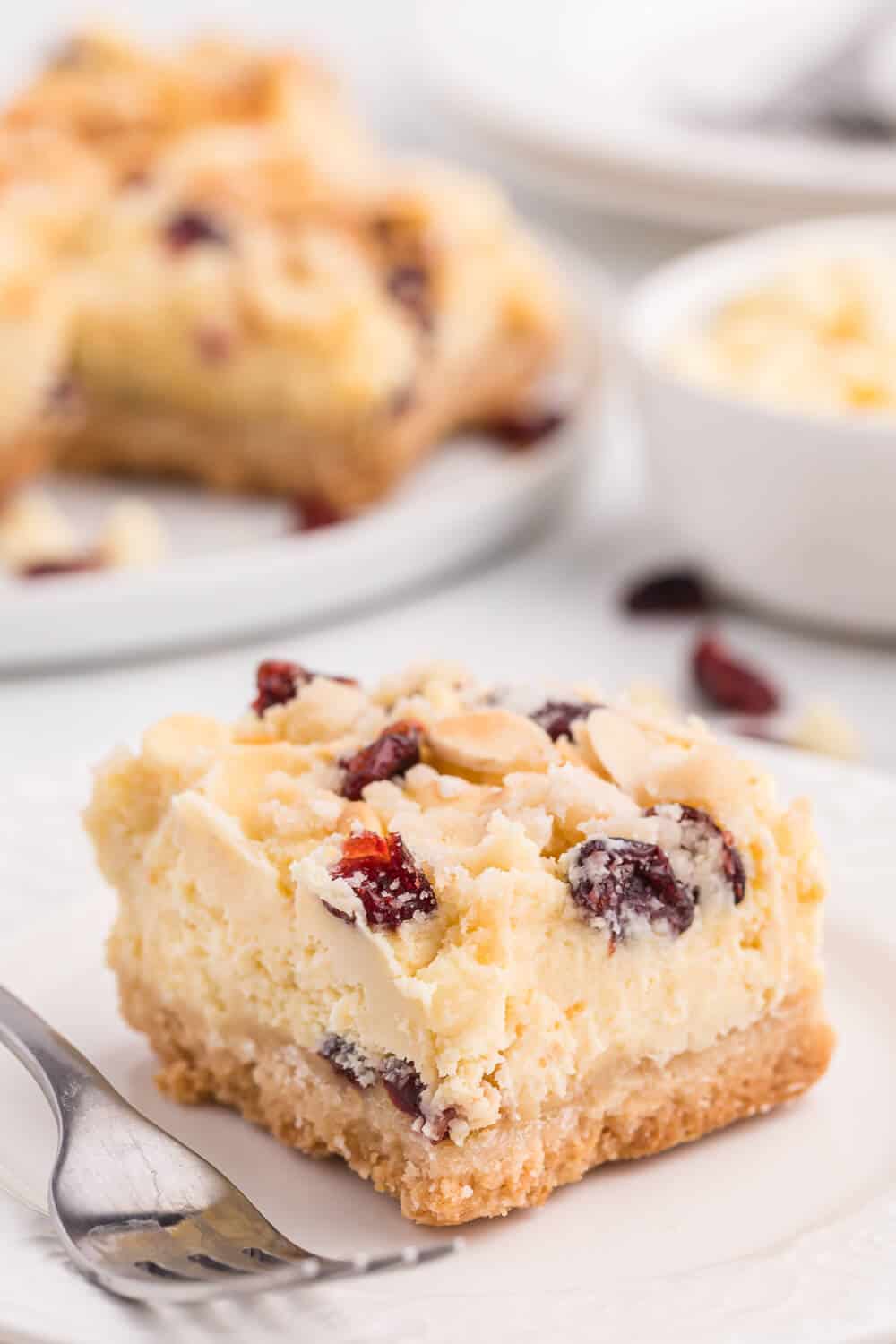 A white chocolate cranberry cheesecake bar on a white plate