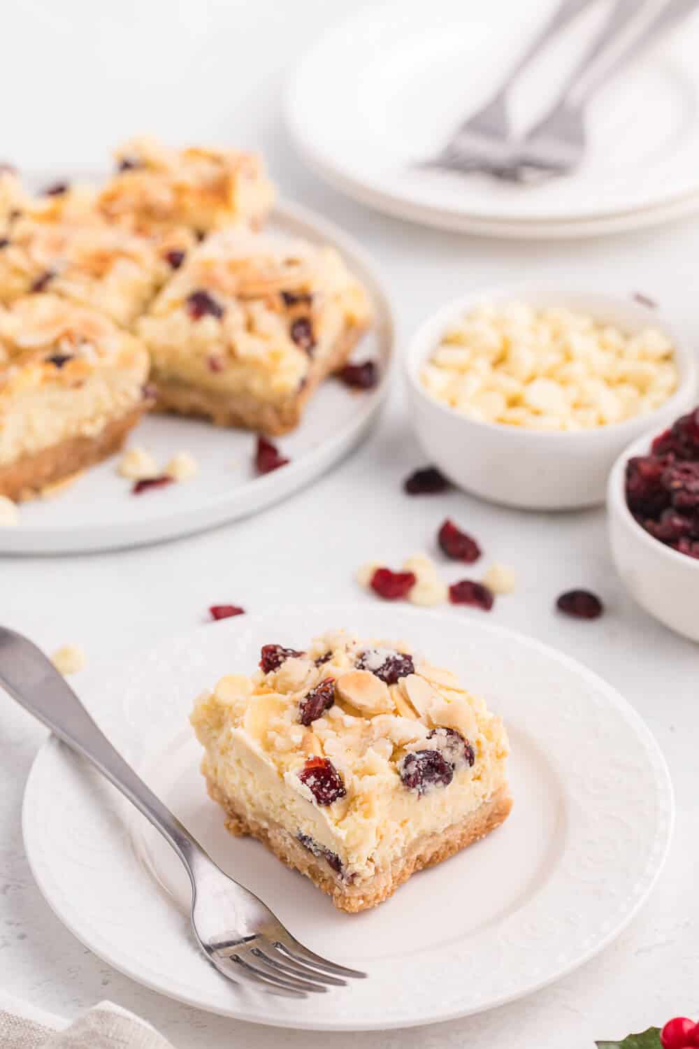 A single white chocolate cranberry cheesecake bar on a white plate