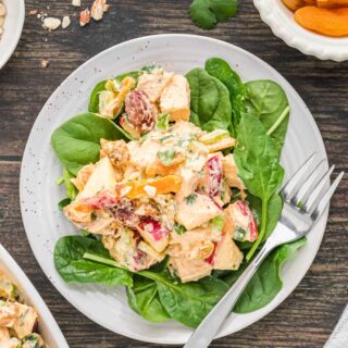 A plate of famous curried chicken salad on a bed of spinach.