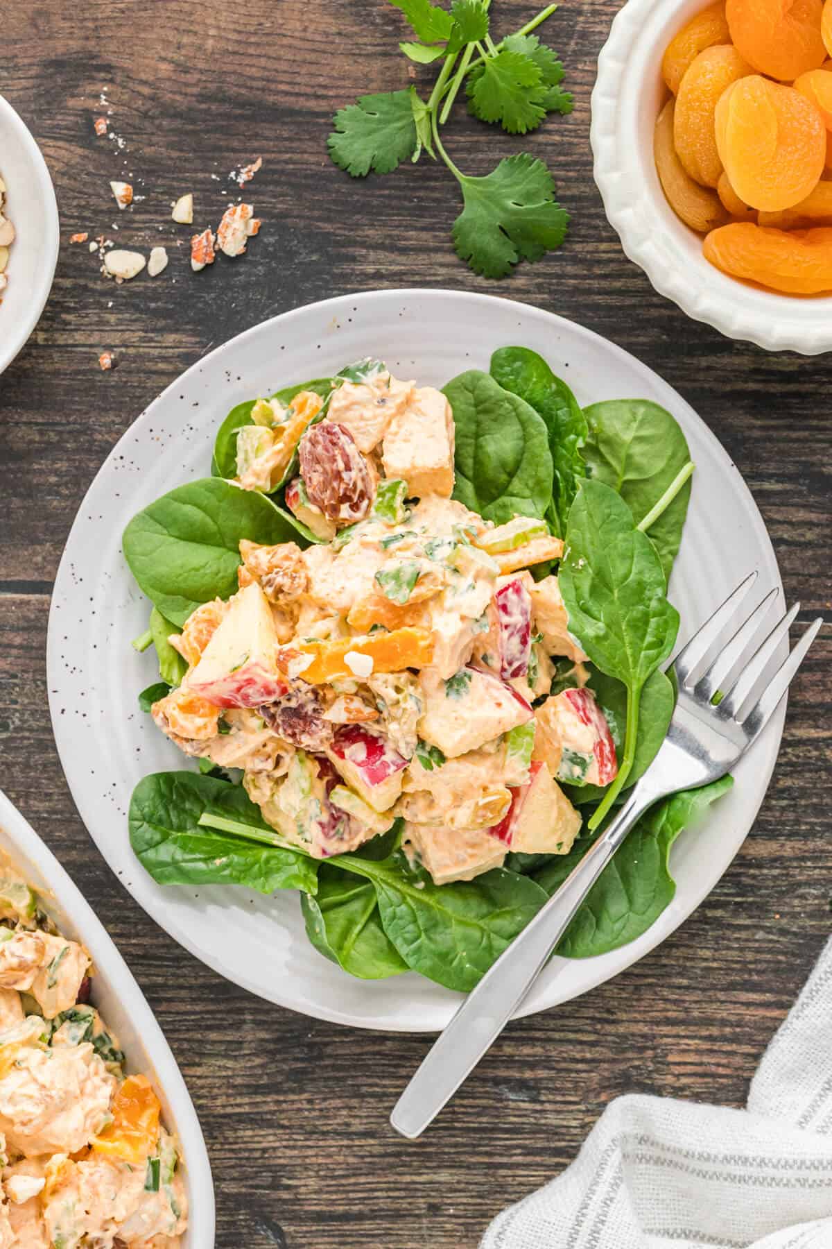 A plate of famous curried chicken salad on a bed of spinach.