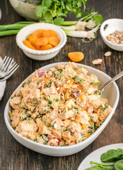 Curried chicken salad in a white serving bowl with a spoon.