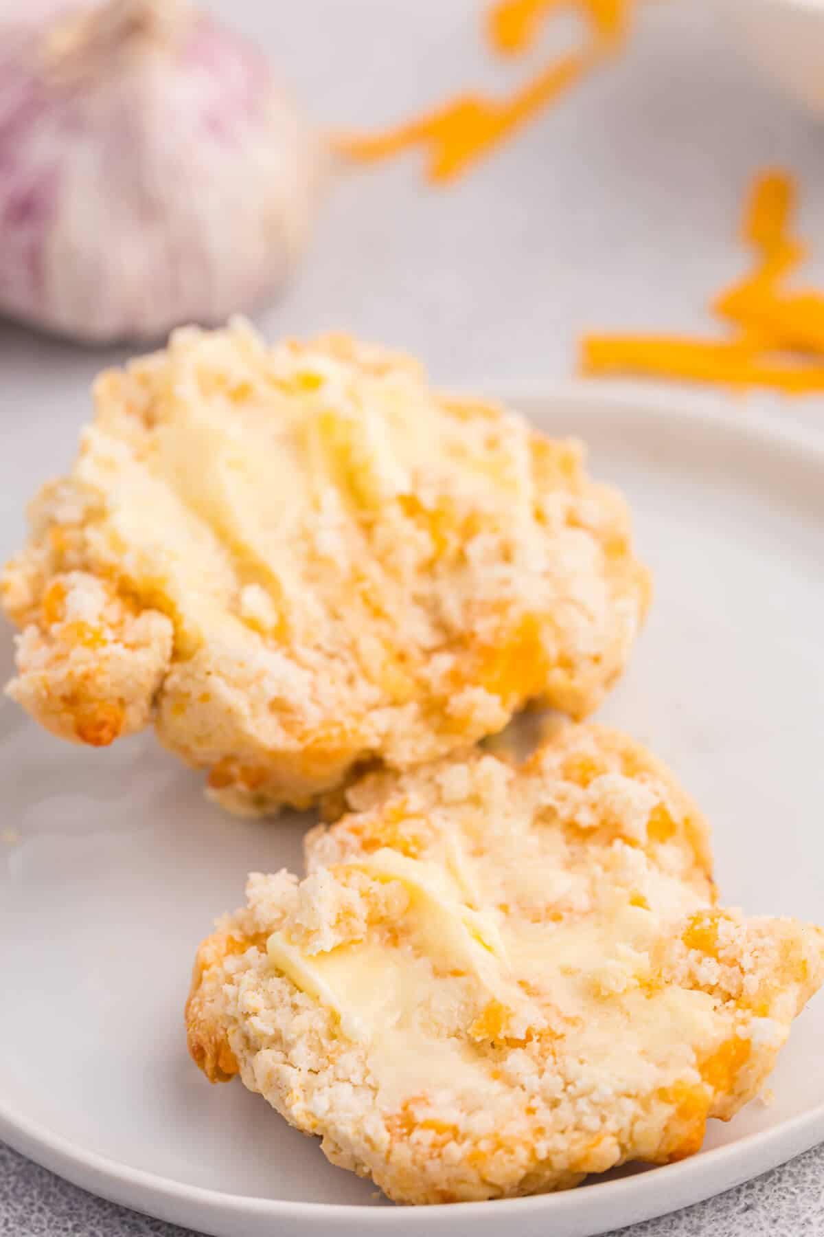 A cheesy garlic biscuit cut in half with butter on it.