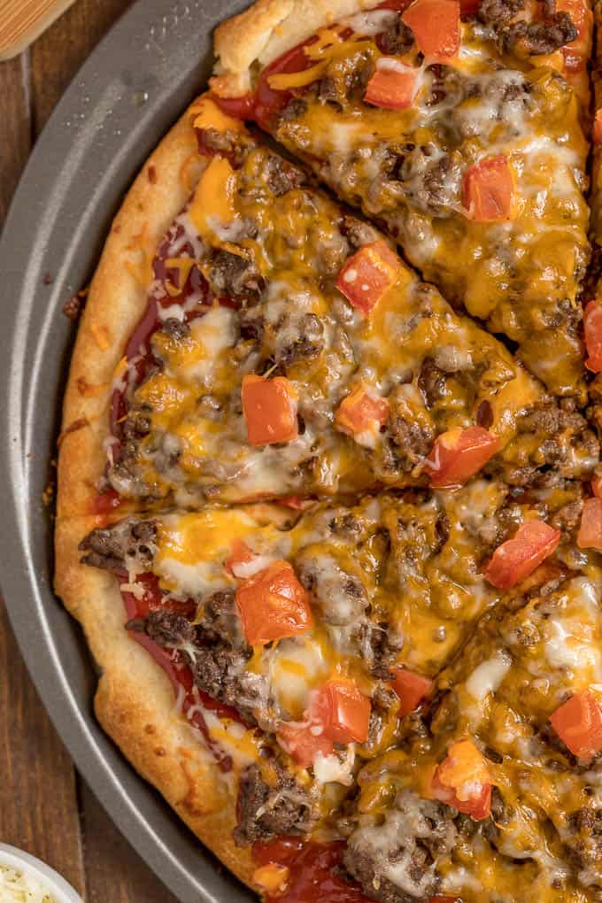 Cheeseburger pizza with slices cut on a pizza pan.