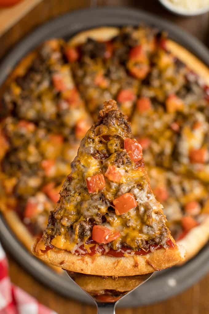 A slice of cheeseburger pizza on a serving spatula.