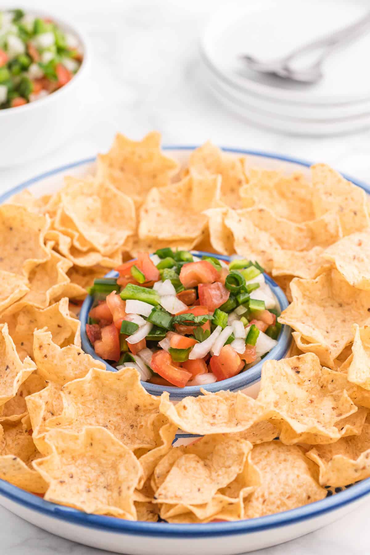 photo pico de gallo on a serving platter surrounded by tortilla chips.