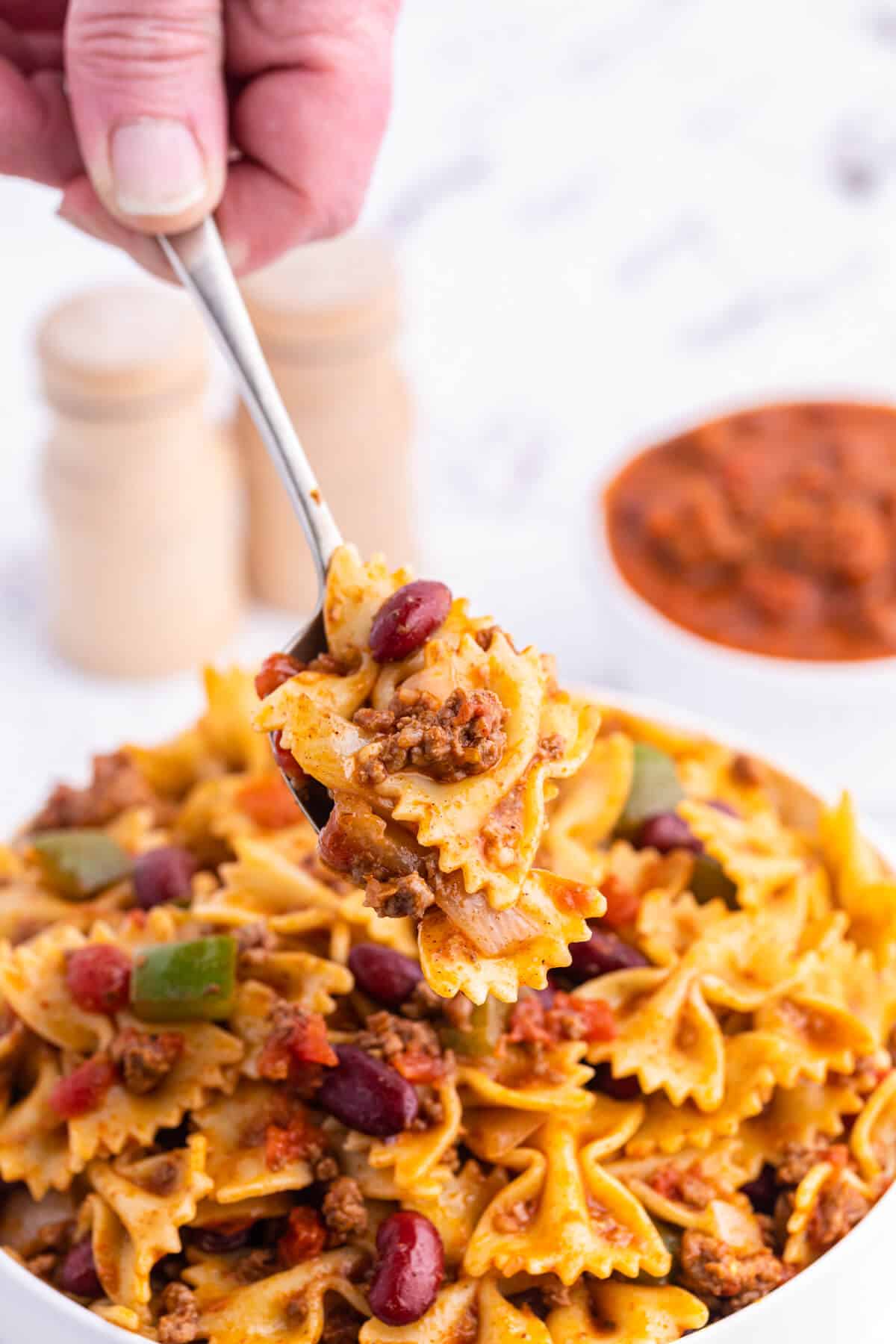A serving spoon with chili pasta salad.