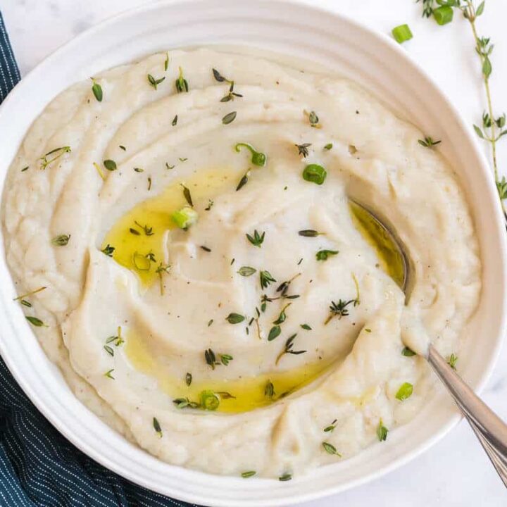 Mashed cauliflower in a bowl with a serving spoon.