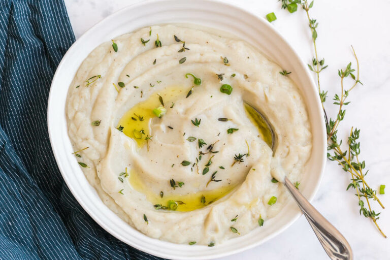 Mashed cauliflower in a bowl with a serving spoon.