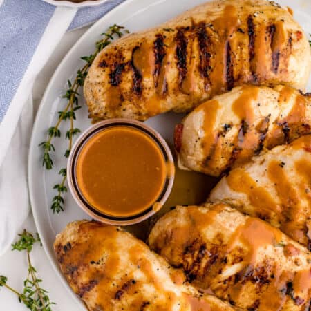 Grilled herb chicken on a plate with sauce.