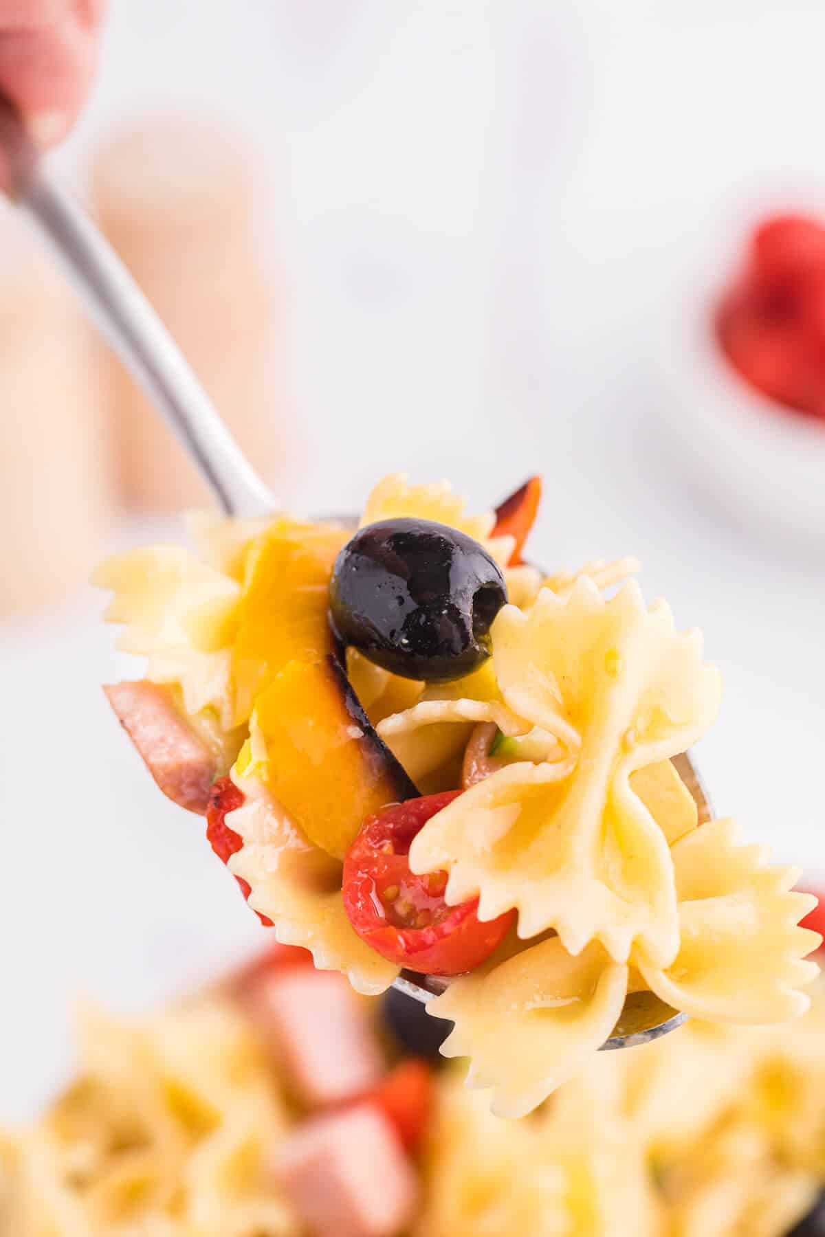 A serving spoon with roasted pepper pasta salad.
