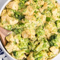 Cheesy chicken and broccoli in a bowl with a wooden spoon.