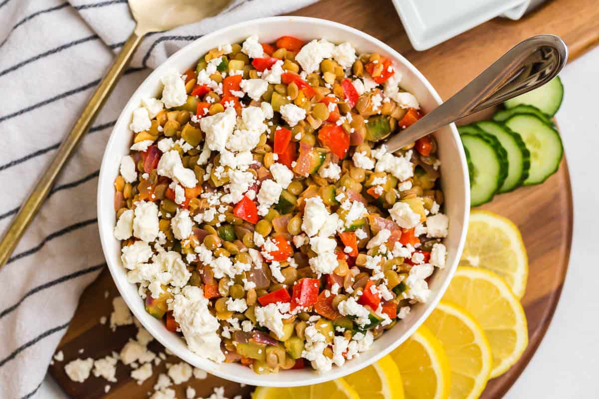 Warm lentil salad in a bowl with a spoon.