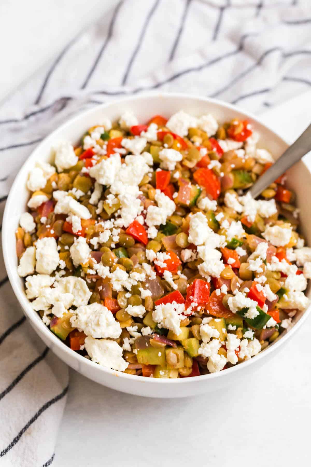 Warm lentil salad in a bowl with a spoon.