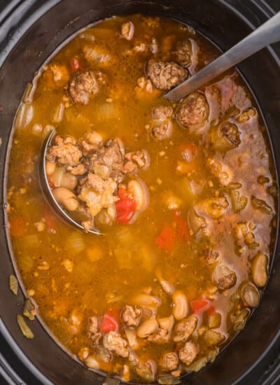Chicken Sausage Soup is the perfect soup to whip up on a chilly day. This slow cooker soup recipe is full of beans, garlic, onion and beer for one savory soup. Pair with dinner rolls and dive in.