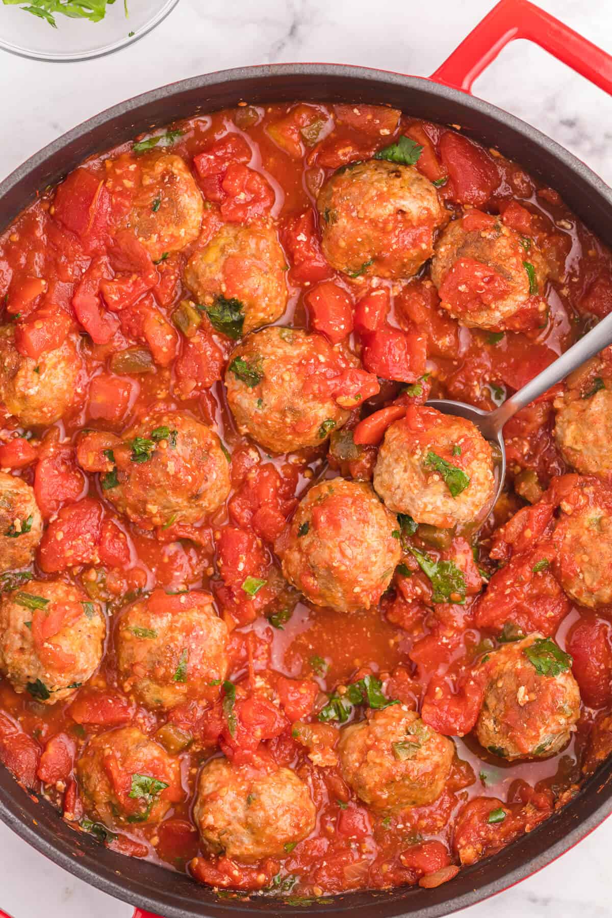 Mexican meatballs in a skillet with a serving spoon.