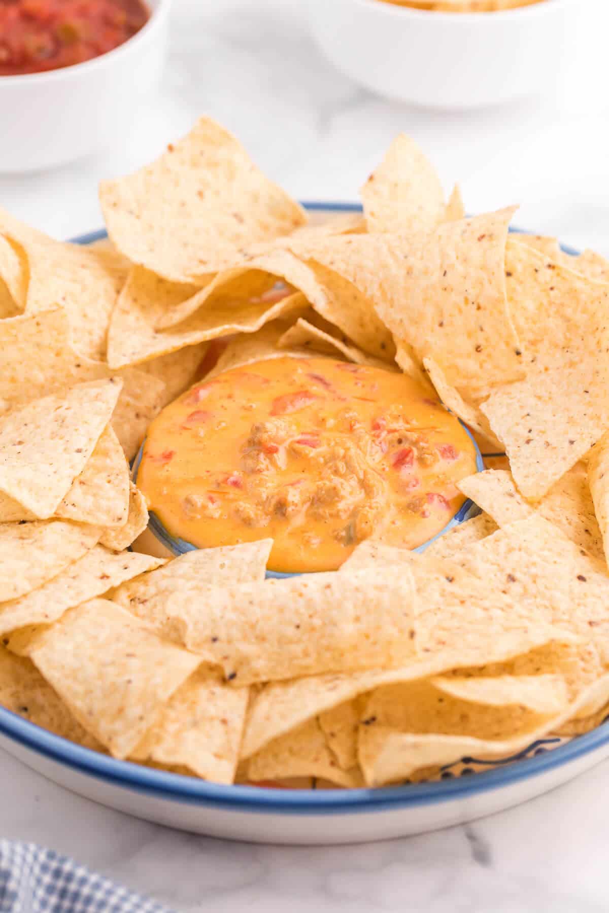 photo of chicken queso dip on a serving platter surrounded by corn tortilla chips.