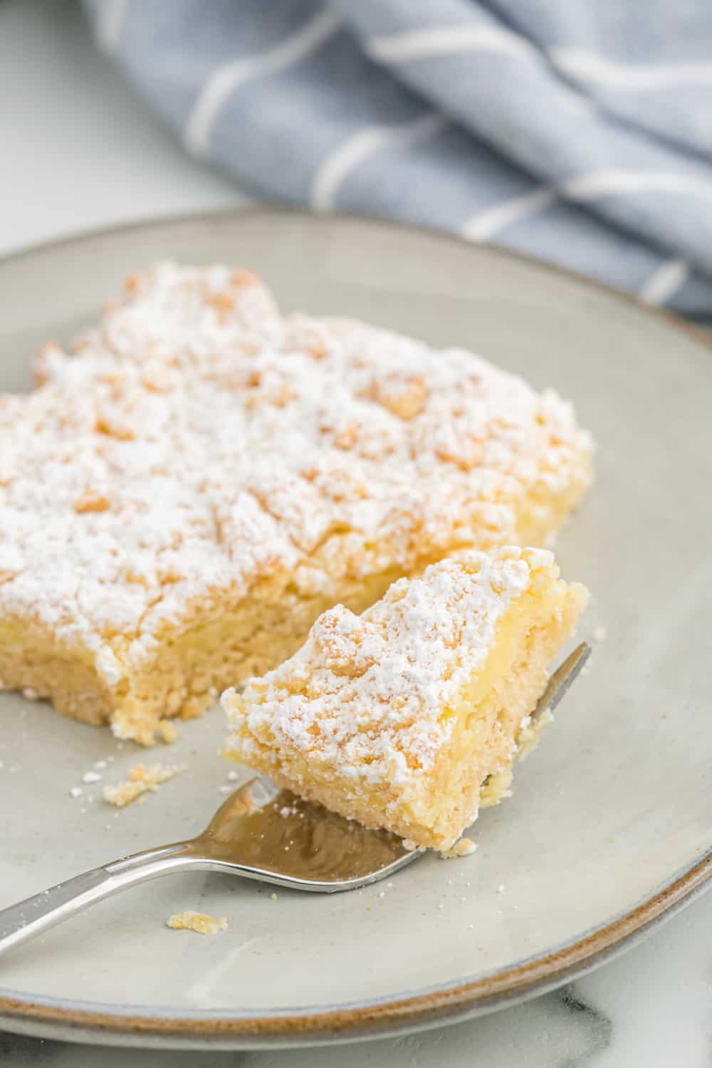 a piece of french vanilla cream bar on plate with a bite on a fork