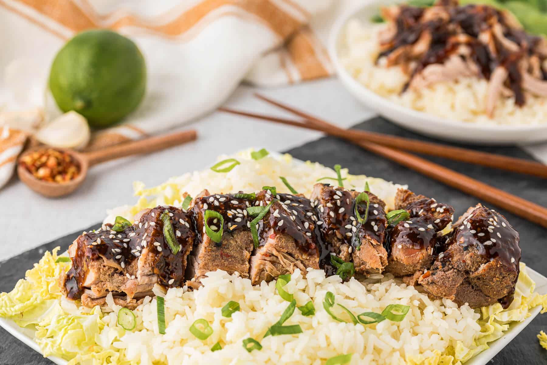 Sliced Asian pork tenderloin on a bed of rice and cabbage.