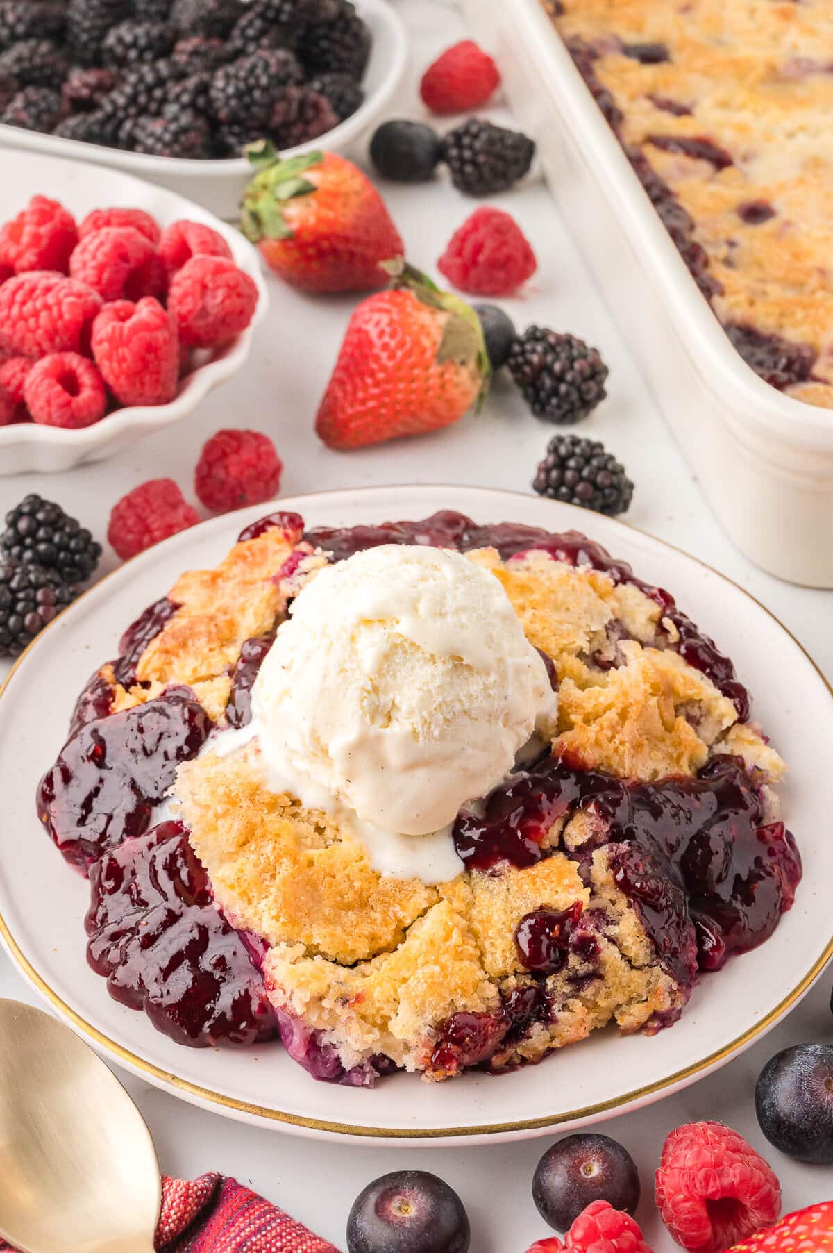A plate of cake mix cobbler topped with a scoop of vanilla ice cream.