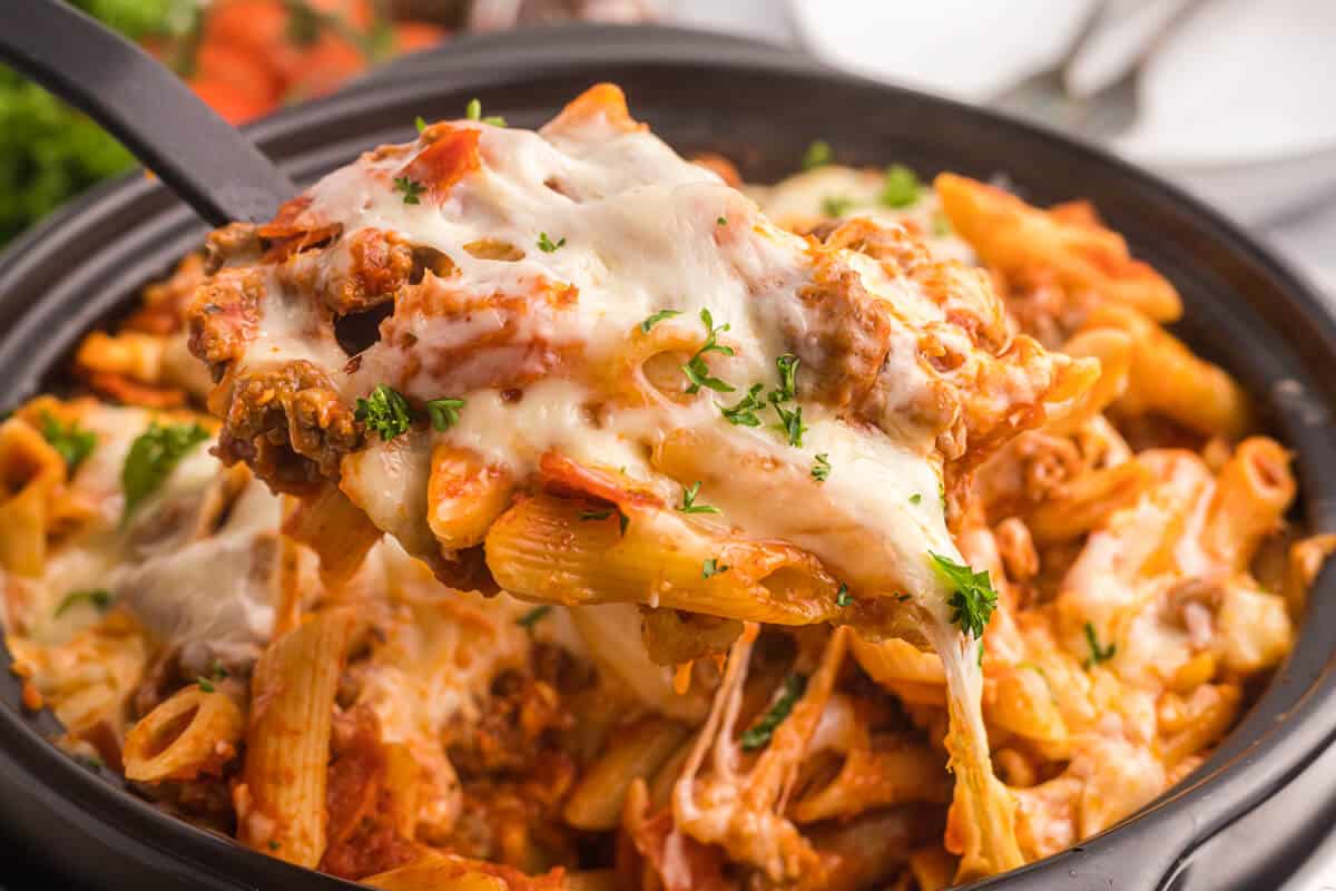 Slow cooker pizza pasta with a serving spoon.