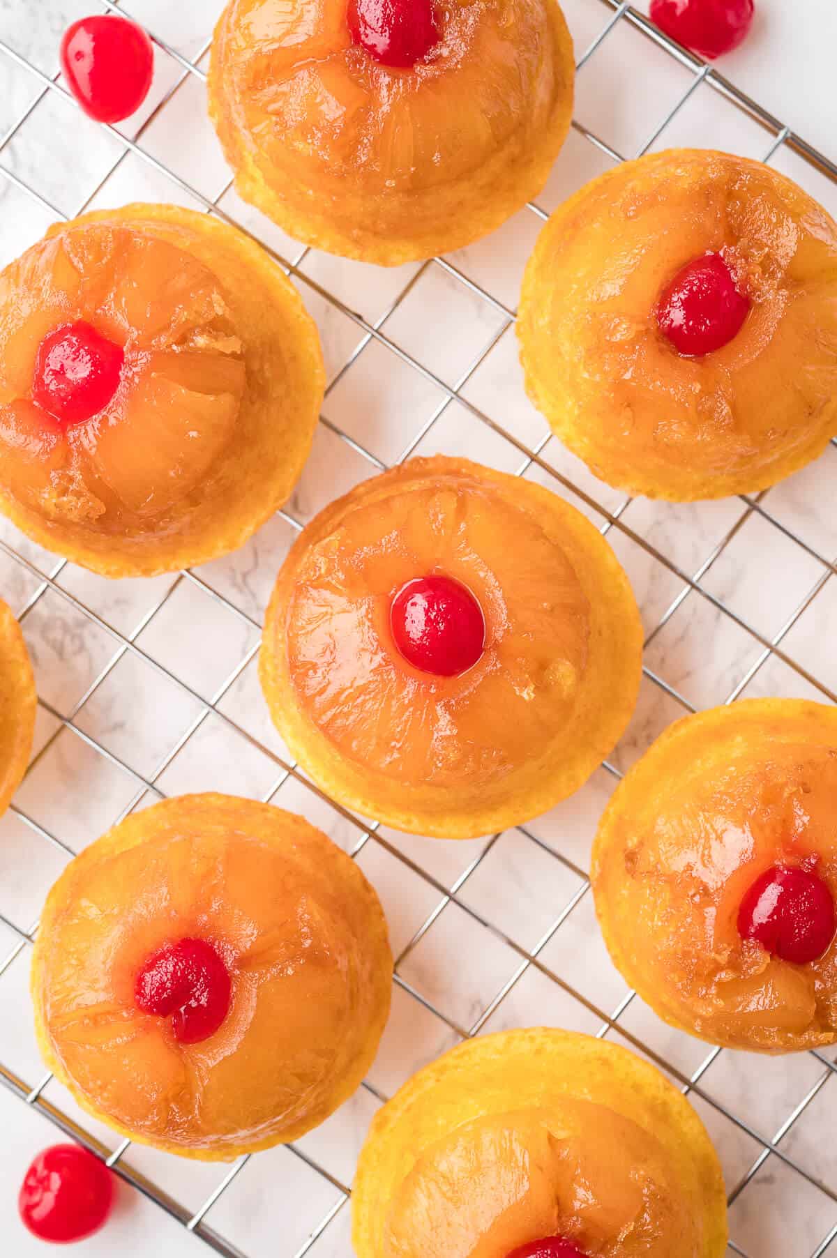 Pineapple upside down cupcakes on a wire rack.