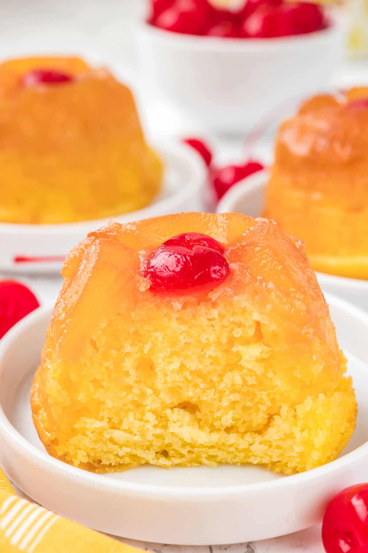 A pineapple upside down cupcake cut in half on a plate.