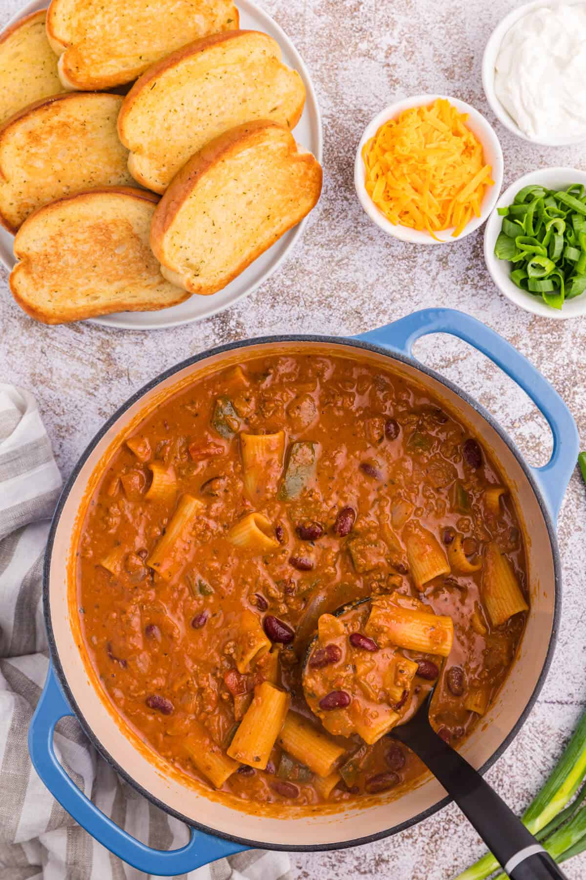 Chili rigatoni in a pot with a ladle.