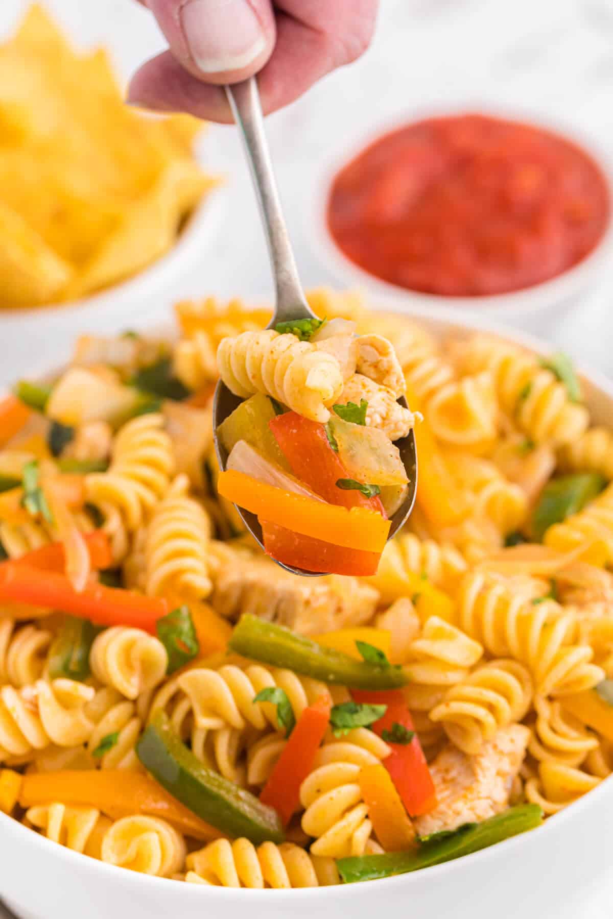 A spoon holding chicken fajita pasta salad.