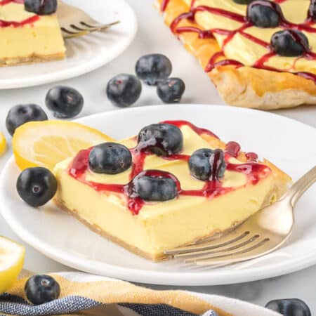 A slice of blueberry lemon tart on a plate with a fork.