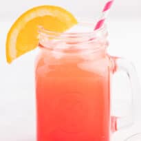 A shirley temple drink in a glass mug with a straw and an orange slice for garnish.