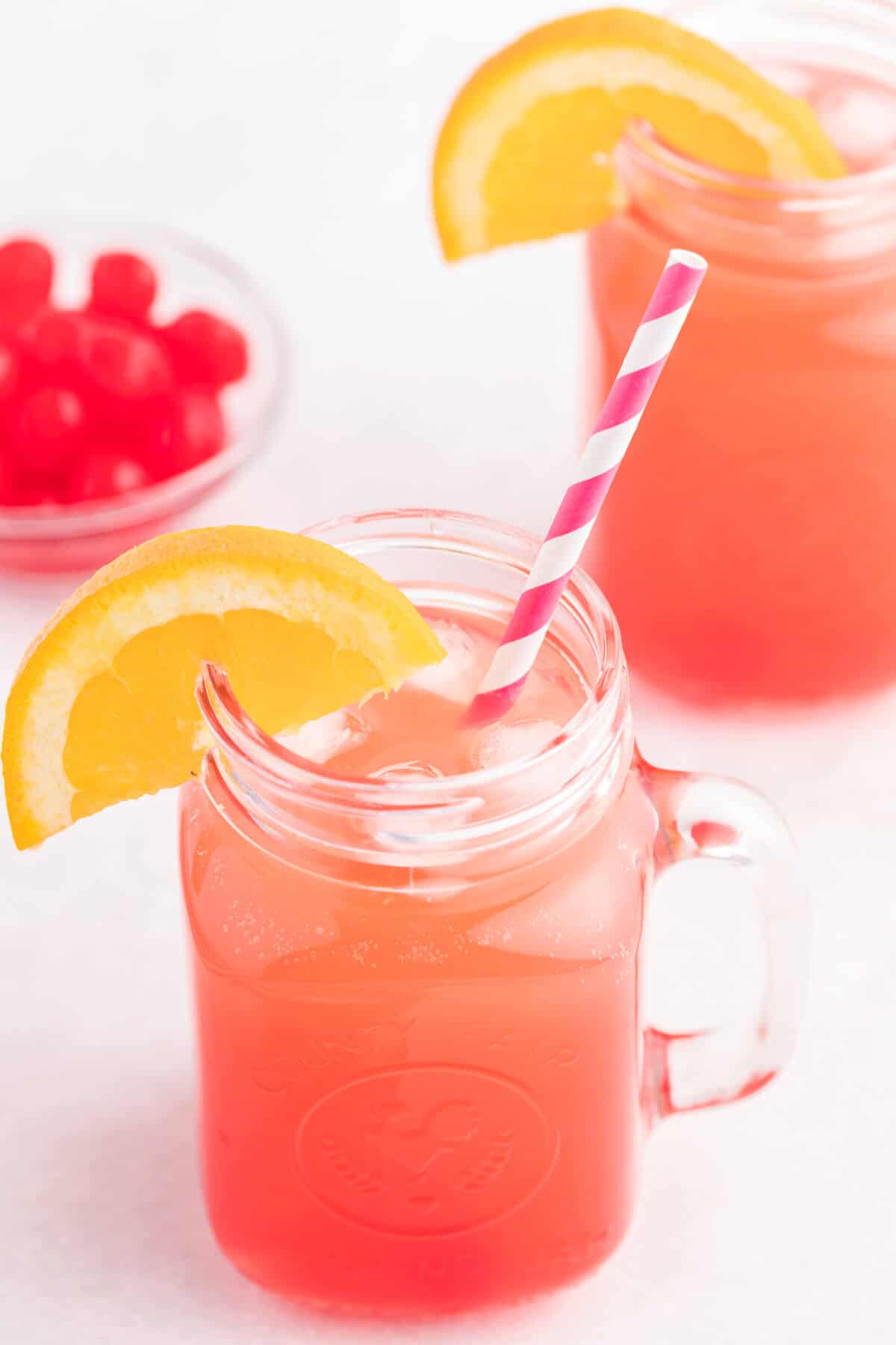 Shirley Temple drink in a glass with a straw and an orange slice.
