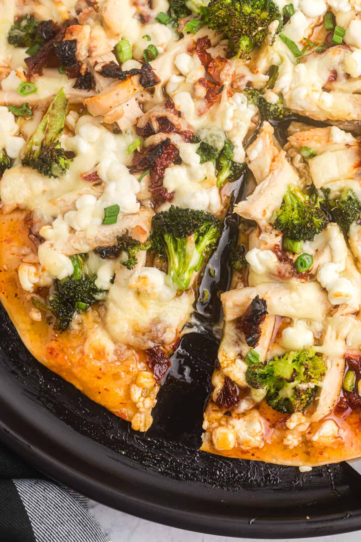A pan of sweet chili chicken thai pizza with slices cut.