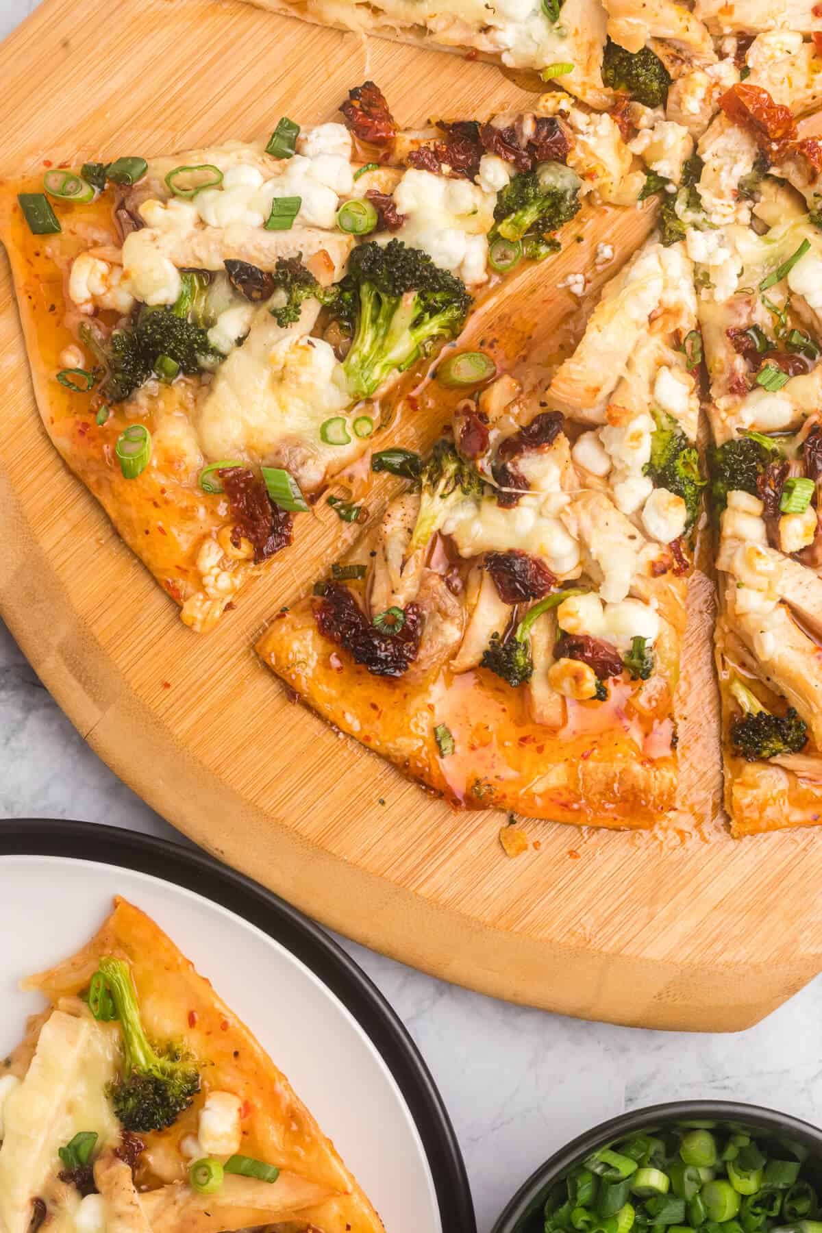 Slices of sweet chili chicken thai pizza on a wooden cutting board.