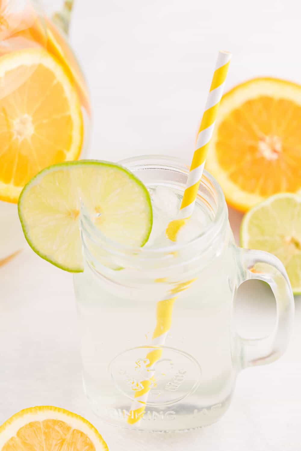 A glass mug of the recipe with a straw and slice of lime.