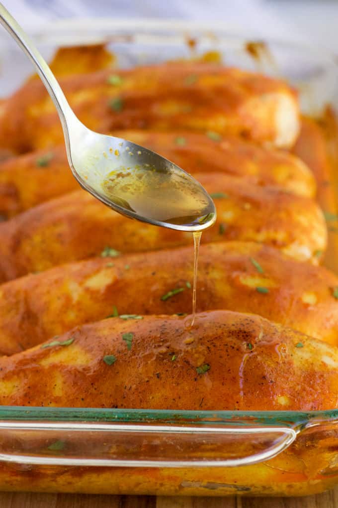 A spoon drizzling the marinade on the chicken.